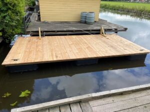 Drijvend terras in het water gelegd naast boot